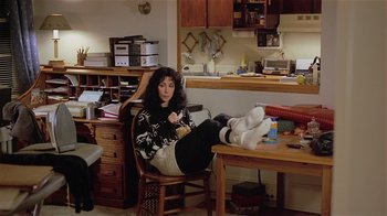 Movie still from “Suspect” (1987), directed by Peter Yates – A woman sitting on a chair in a room; Wide shot, High angle
