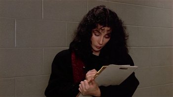 Movie still from “Suspect” (1987), directed by Peter Yates – A woman writing on a piece of paper in front of a brick wall; Close Up shot, Over the shoulder angle