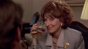 Movie still from “Suspect” (1987), directed by Peter Yates – A woman holding a glass in her hand; Close Up shot, Over the shoulder angle