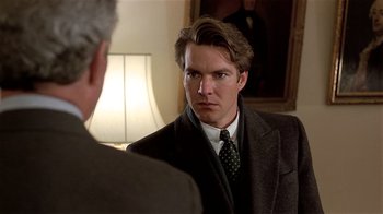 Movie still from “Suspect” (1987), directed by Peter Yates – A man wearing a suit and tie in front of a mirror; Close Up shot, Over the shoulder angle