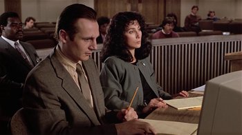 Movie still from “Suspect” (1987), directed by Peter Yates – A man and a woman sitting at a table in a courtroom; Medium shot, Low angle