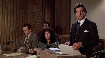 Movie still from “Suspect” (1987), directed by Peter Yates – A man and two women in a court room; Medium shot, High angle
