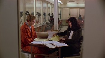 Movie still from “Suspect” (1987), directed by Peter Yates – A man and a woman sitting at a table with papers on it; Wide shot, High angle
