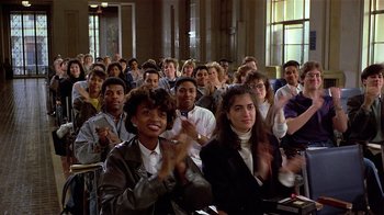 Movie still from “Suspect” (1987), directed by Peter Yates – A group of people sitting and clapping in a room; Medium shot, High angle