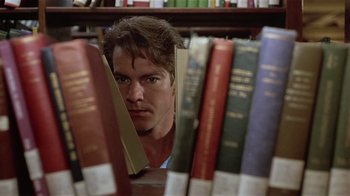 Movie still from “Suspect” (1987), directed by Peter Yates – A man is looking through a bunch of books in a library; Close Up shot, Low angle