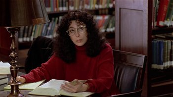 Movie still from “Suspect” (1987), directed by Peter Yates – A woman sitting at a table in a library; Medium shot, High angle