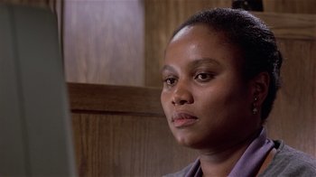 Movie still from “Suspect” (1987), directed by Peter Yates – A person sitting in front of a wooden wall; Close Up shot, Over the shoulder angle