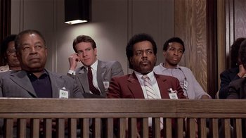 Movie still from “Suspect” (1987), directed by Peter Yates – A group of men sitting in front of each other in a courtroom; Medium shot, Low angle