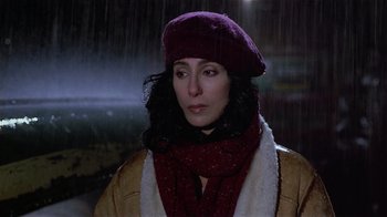Movie still from “Suspect” (1987), directed by Peter Yates – A woman wearing a purple hat and a scarf in the rain; Close Up shot, High angle