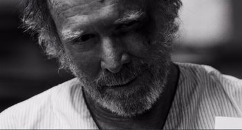 Movie still from “Sweet Thing” (2020), directed by Alexandre Rockwell – An old man with a beard and a white shirt; Extreme Close Up shot, High angle