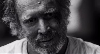 Movie still from “Sweet Thing” (2020), directed by Alexandre Rockwell – An old man with a beard and a piercing on his forehead; Close Up shot, Over the shoulder angle