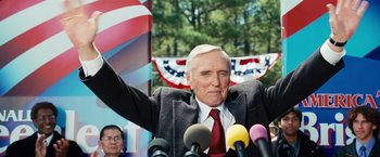 Movie still from “Swing Vote” (2008), directed by Joshua Michael Stern – An older man is speaking at a political event; Medium shot, Low angle