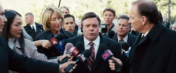 Movie still from “Swing Vote” (2008), directed by Joshua Michael Stern – A group of people holding microphones in front of a man; Medium shot, Over the shoulder angle