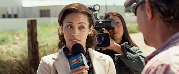 Movie still from “Swing Vote” (2008), directed by Joshua Michael Stern – A woman is holding a microphone while a man is taking a picture of her; Close Up shot, Over the shoulder angle