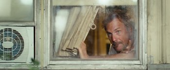 Movie still from “Swing Vote” (2008), directed by Joshua Michael Stern – A man looking out of a window at a building; Close Up shot, Low angle