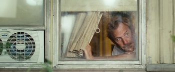 Movie still from “Swing Vote” (2008), directed by Joshua Michael Stern – A man is peeking through a window and holding a piece of wood; Close Up shot, Low angle