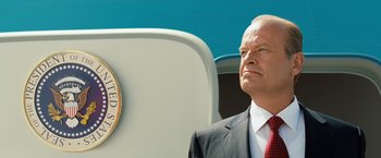 Movie still from “Swing Vote” (2008), directed by Joshua Michael Stern – A man in a suit and red tie standing next to a seal; Close Up shot, Low angle