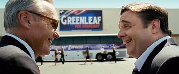 Movie still from “Swing Vote” (2008), directed by Joshua Michael Stern – Two men standing next to each other in front of a bus; Medium shot, Over the shoulder angle