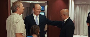 Movie still from “Swing Vote” (2008), directed by Joshua Michael Stern – A man in a suit and tie standing next to two other men; Medium shot, Over the shoulder angle