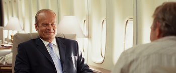 Movie still from “Swing Vote” (2008), directed by Joshua Michael Stern – A man in a suit sitting on top of an airplane; Close Up shot, Over the shoulder angle
