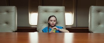 Movie still from “Swing Vote” (2008), directed by Joshua Michael Stern – A young girl sitting in a chair holding a cup in her hand; Medium shot, Low angle