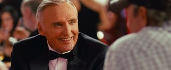 Movie still from “Swing Vote” (2008), directed by Joshua Michael Stern – An older man in a tuxedo smiling at the camera; Close Up shot, Over the shoulder angle