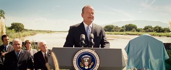 Movie still from “Swing Vote” (2008), directed by Joshua Michael Stern – A man standing at a podium with microphones in front of him; Medium shot, Over the shoulder angle