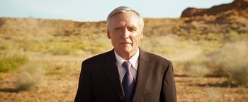 Movie still from “Swing Vote” (2008), directed by Joshua Michael Stern – An older man wearing a suit and tie in the desert; Medium shot, Low angle