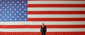 Movie still from “Swing Vote” (2008), directed by Joshua Michael Stern – A man standing in front of an american flag; Extreme Wide shot, Low angle
