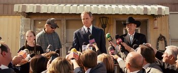 Movie still from “Swing Vote” (2008), directed by Joshua Michael Stern – A man in a business suit being interviewed by reporters; Medium shot, Over the shoulder angle