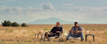 Movie still from “Swing Vote” (2008), directed by Joshua Michael Stern – Two men sitting in lawn chairs in the middle of a field; Wide shot, Low angle