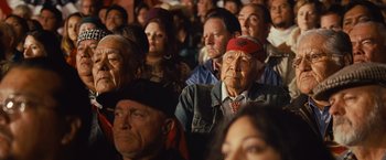Movie still from “Swing Vote” (2008), directed by Joshua Michael Stern – A group of people sitting in a room; Medium shot, Over the shoulder angle