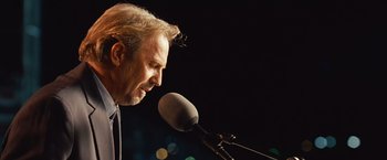 Movie still from “Swing Vote” (2008), directed by Joshua Michael Stern – A man is speaking into a microphone on a stage; Close Up shot, Low angle