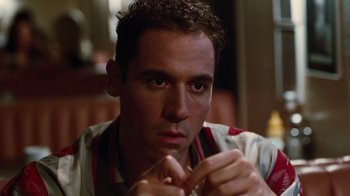 Movie still from “Swingers” (1996), directed by Doug Liman – A person sitting down with a pen in his mouth; Close Up shot, Over the shoulder angle