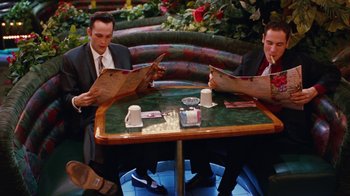 Movie still from “Swingers” (1996), directed by Doug Liman – A couple of men sitting at a table reading papers; Wide shot, High angle