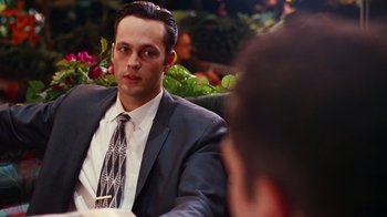 Movie still from “Swingers” (1996), directed by Doug Liman – A man in a suit and tie sitting in front of another man in a suit; Close Up shot, Over the shoulder angle