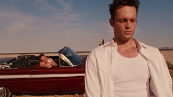 Movie still from “Swingers” (1996), directed by Doug Liman – A man sitting in the back of a red car next to another man; Medium shot, Over the shoulder angle