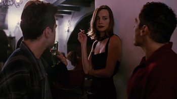Movie still from “Swingers” (1996), directed by Doug Liman – A woman smoking a cigarette in front of two other people; Medium shot, Over the shoulder angle