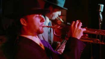 Movie still from “Swingers” (1996), directed by Doug Liman – A man in a purple suit and a hat is blowing into a trumpet; Extreme Close Up shot, Low angle