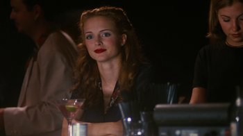Movie still from “Swingers” (1996), directed by Doug Liman – A woman sitting at a table with a drink in front of her; Close Up shot, Over the shoulder angle