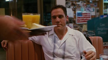 Movie still from “Swingers” (1996), directed by Doug Liman – A man sitting in front of a plate of food; Medium shot, Low angle