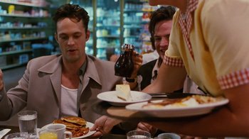Movie still from “Swingers” (1996), directed by Doug Liman – A group of people sitting at a table with plates of food; Medium shot, Over the shoulder angle