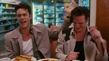 Movie still from “Swingers” (1996), directed by Doug Liman – Two men sitting at a table with plates of food in front of them; Medium shot, Low angle