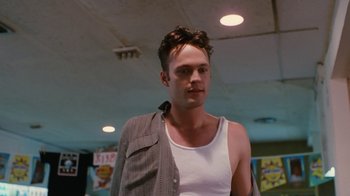 Movie still from “Swingers” (1996), directed by Doug Liman – A man in a white tank top is standing in a room; Close Up shot, Low angle