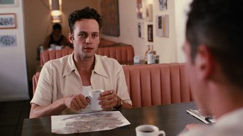 Movie still from “Swingers” (1996), directed by Doug Liman – A man sitting at a table holding a coffee cup; Medium shot, Over the shoulder angle