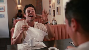 Movie still from “Swingers” (1996), directed by Doug Liman – A man sitting at a table with a napkin in front of his face; Medium shot, Low angle