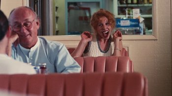 Movie still from “Swingers” (1996), directed by Doug Liman – A woman sitting in a booth at a restaurant with her mouth wide open; Medium shot, Over the shoulder angle