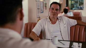 Movie still from “Swingers” (1996), directed by Doug Liman – A man sitting at a table with a cup of coffee in front of him; Medium shot, Over the shoulder angle