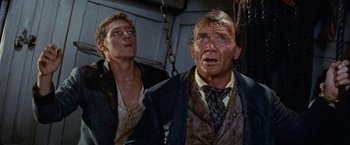 Movie still from “Swiss Family Robinson” (1960), directed by Ken Annakin – A man and a man in a suit and tie looking at something; Close Up shot, Low angle
