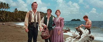 Movie still from “Swiss Family Robinson” (1960), directed by Ken Annakin – Two men and a woman standing on the beach; Medium shot, Low angle